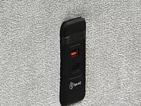 Gros plan sur la prise USB intégrée à l’accoudoir du canapé-lit gris moderne – Literie d’Amitié